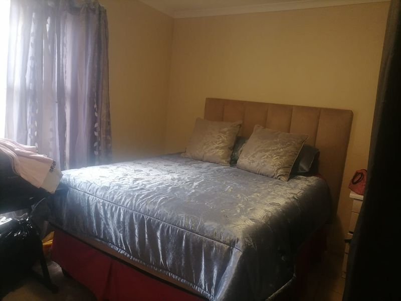 A standard bedroom featuring a built-in headboard and neutral wall finishes, offering a functional space for rest.