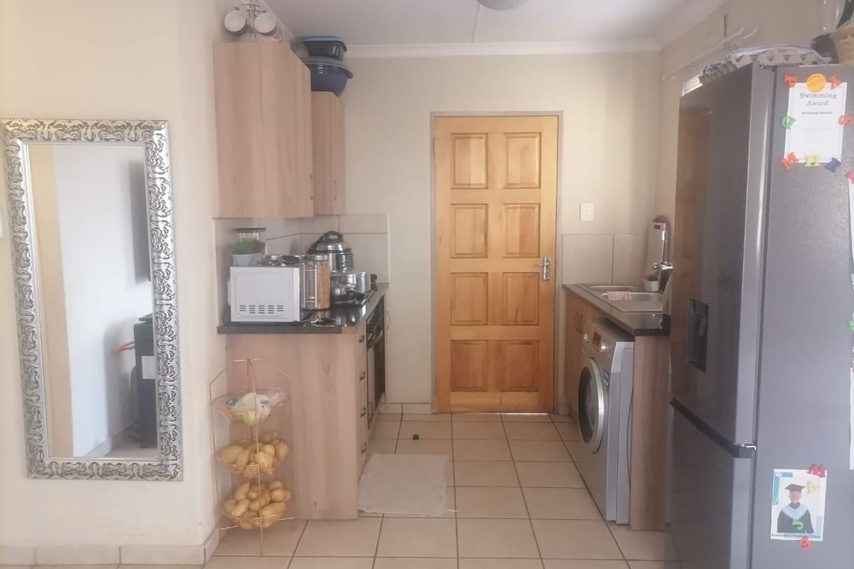 A functional kitchen featuring laminate cabinetry, tiled flooring, and a solid wood door, providing a practical layout for daily meal preparation.