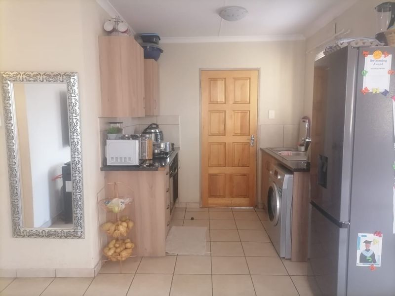 A functional kitchen featuring laminate cabinetry, tiled flooring, and a solid wood door, providing a practical layout for daily meal preparation.