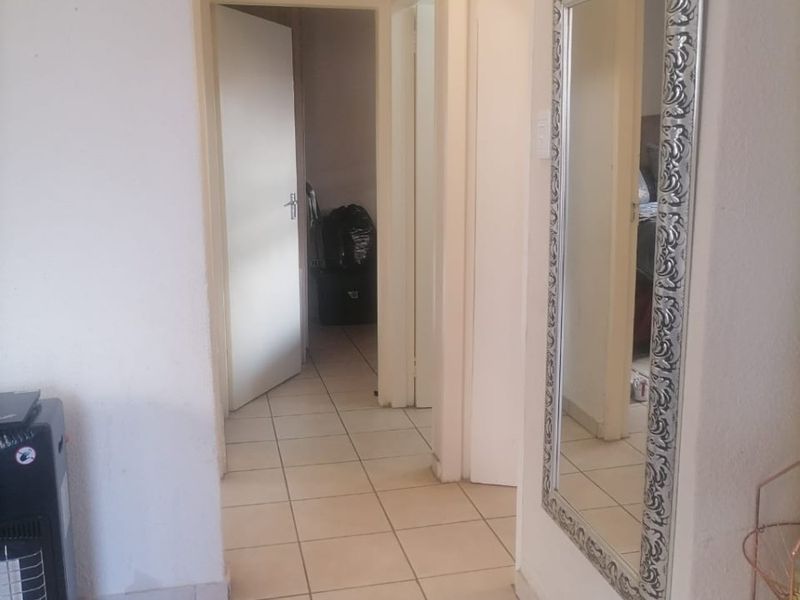 A functional hallway featuring neutral tiled flooring and access to multiple rooms within the home.
