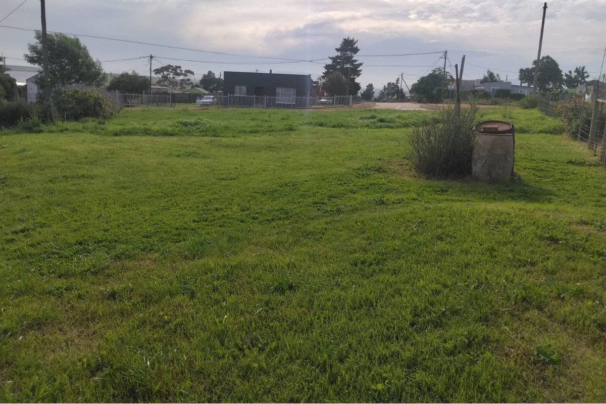 A vacant residential plot featuring open grass, perimeter fencing, and utility infrastructure, offering a clear space for potential development.