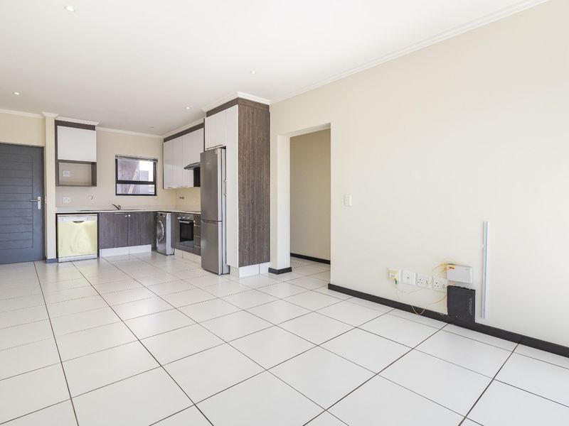 An open-plan living and kitchen area featuring modern cabinetry, tiled flooring, and recessed lighting, offering a clean and functional space.