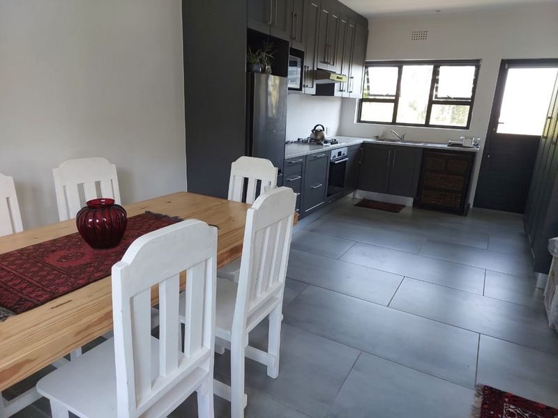 Open-plan kitchen and dining area featuring modern dark grey cabinetry, built-in appliances, and large format floor tiles.