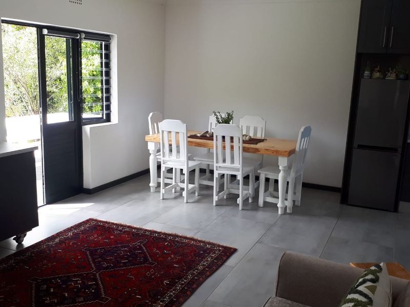 An open-plan living and dining area featuring modern tiled flooring, dark cabinetry, and a sliding door providing access to the outdoors.
