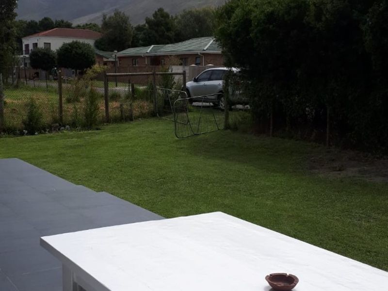 A paved outdoor patio area overlooking a private garden with scenic mountain views in the background.
