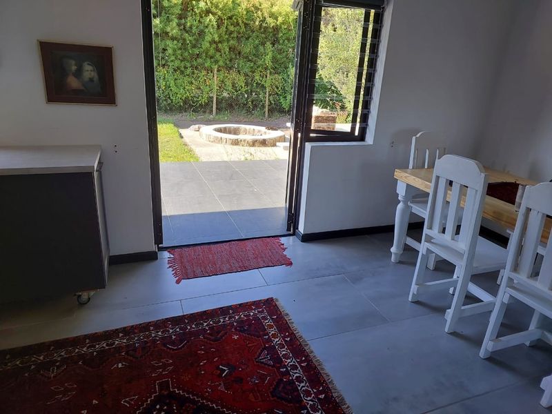 Open plan living area featuring tiled floors and large sliding doors providing direct access to an outdoor patio and garden area.