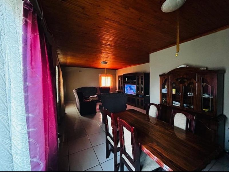 Open plan living and dining area featuring tiled flooring and a warm timber tongue and groove ceiling.