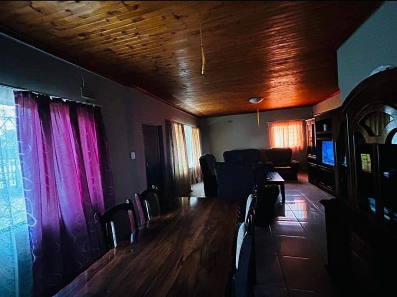 Open plan living and dining area featuring a timber tongue and groove ceiling and ceramic floor tiles.