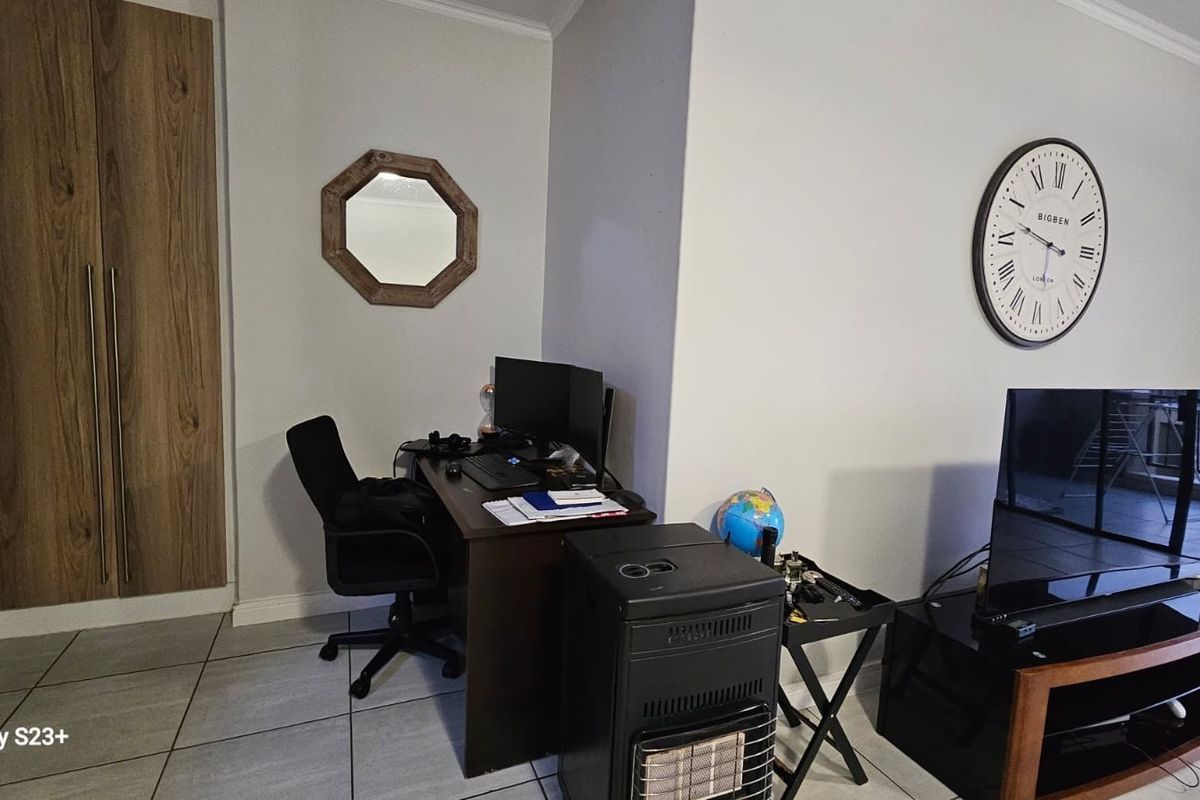 A living area featuring tiled flooring and a built-in cupboard, currently utilized as a multi-functional space.
