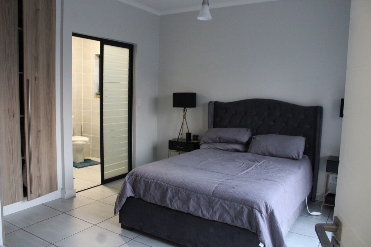 A well-maintained bedroom featuring tiled flooring, a built-in wardrobe, and direct access to an en-suite bathroom through a modern sliding door.