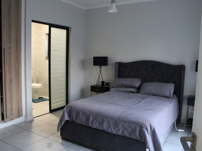 A well-maintained bedroom featuring tiled flooring, a built-in wardrobe, and direct access to an en-suite bathroom through a modern sliding door.