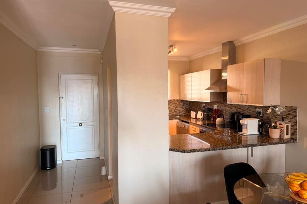 Open plan kitchen featuring granite countertops, mosaic backsplash, and modern cabinetry, seamlessly flowing into the entrance hallway with tiled flooring throughout.