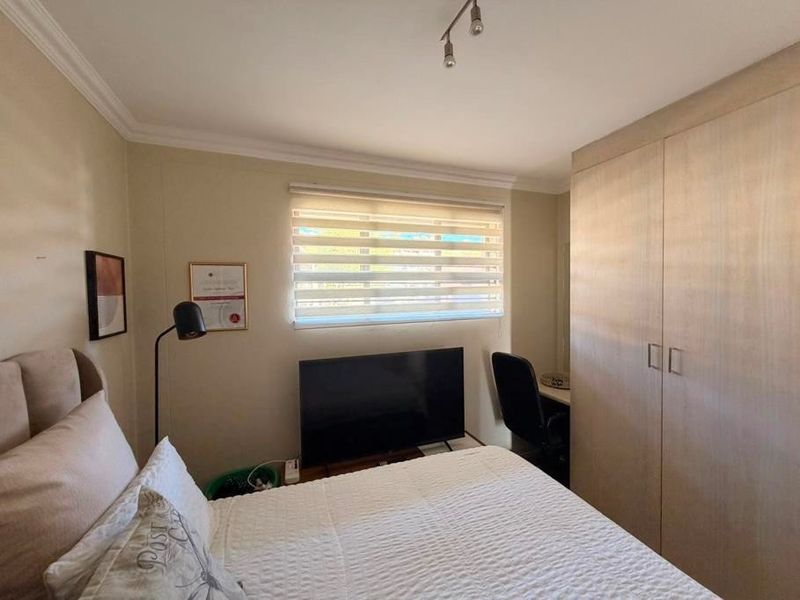 A well-maintained bedroom featuring built-in wardrobes, neutral wall finishes, and modern window blinds, providing a functional and comfortable living space.