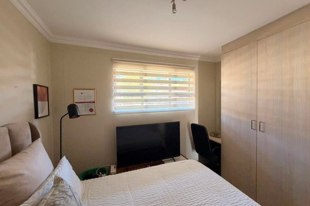 A well-maintained bedroom featuring built-in wardrobes, neutral wall finishes, and modern window blinds, providing a functional and comfortable living space.