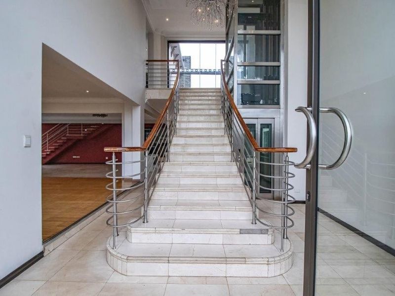 Grand entrance foyer featuring a sweeping marble staircase with stainless steel balustrades and a modern integrated glass elevator.