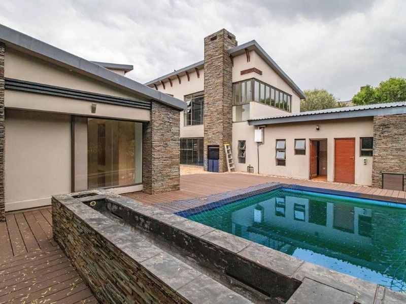 Rear exterior view featuring a swimming pool, timber decking, and stone-clad architectural elements with multi-level building structures.
