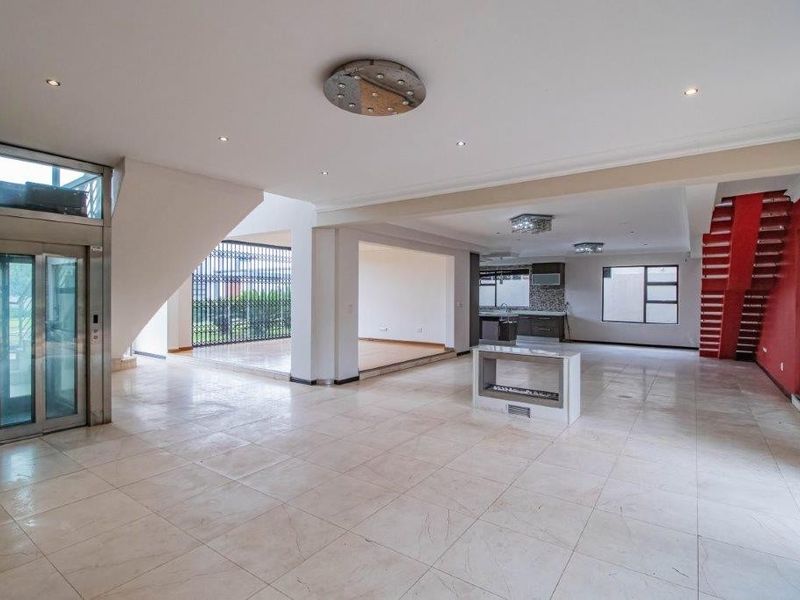 Spacious open-plan living area featuring a built-in elevator, central fireplace, tiled flooring, and recessed lighting, offering a versatile layout for modern living.