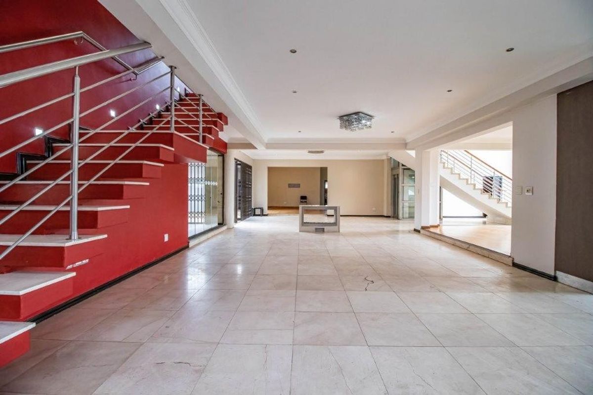 Spacious open-plan living area featuring a prominent red staircase with stainless steel balustrades and large format floor tiles.