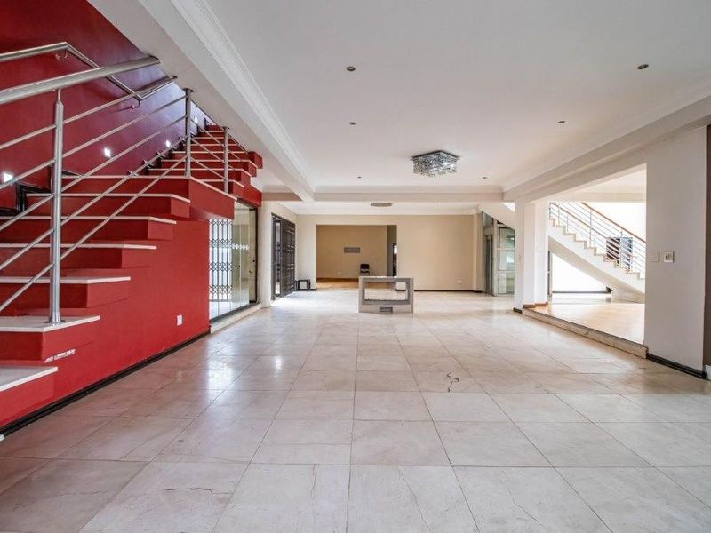 Spacious open-plan living area featuring a prominent red staircase with stainless steel balustrades and large format floor tiles.