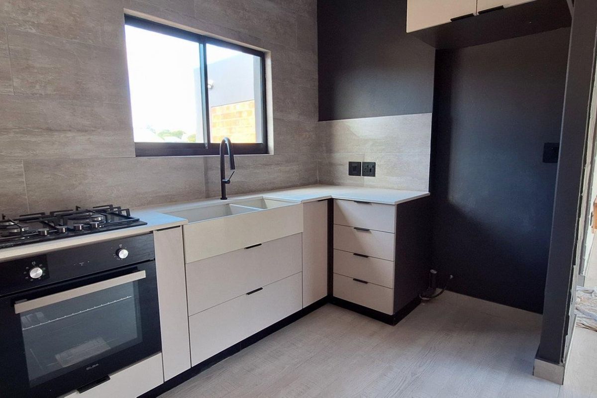Modern kitchen featuring sleek cabinetry, stone countertops, a built-in oven with gas hob, and a double basin sink with contemporary fixtures.