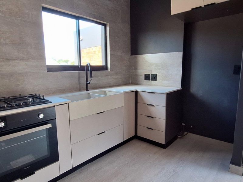 Modern kitchen featuring sleek cabinetry, stone countertops, a built-in oven with gas hob, and a double basin sink with contemporary fixtures.