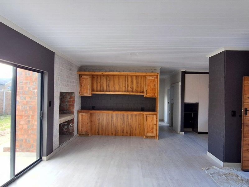 Spacious living area featuring built-in wooden cabinetry, an exposed brick fireplace, and large sliding glass doors providing access to the garden.