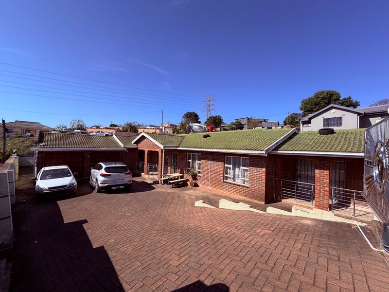 Front view of a single-story brick house featuring a tiled roof, paved driveway, and integrated garage space.
