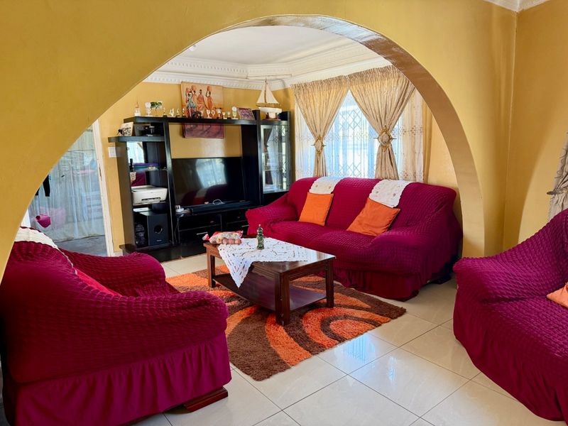 A living room featuring a prominent arched entryway, tiled flooring, and decorative ceiling cornicing, providing a traditional layout with ample natural light.