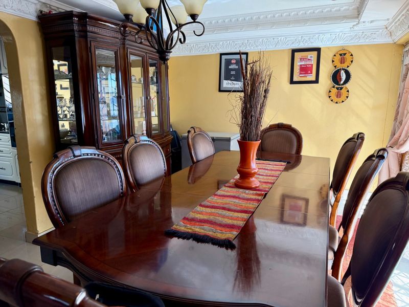 A formal dining room featuring ornate ceiling cornicing, a decorative ceiling rose, and tiled flooring, providing a classic foundation for a dining space.