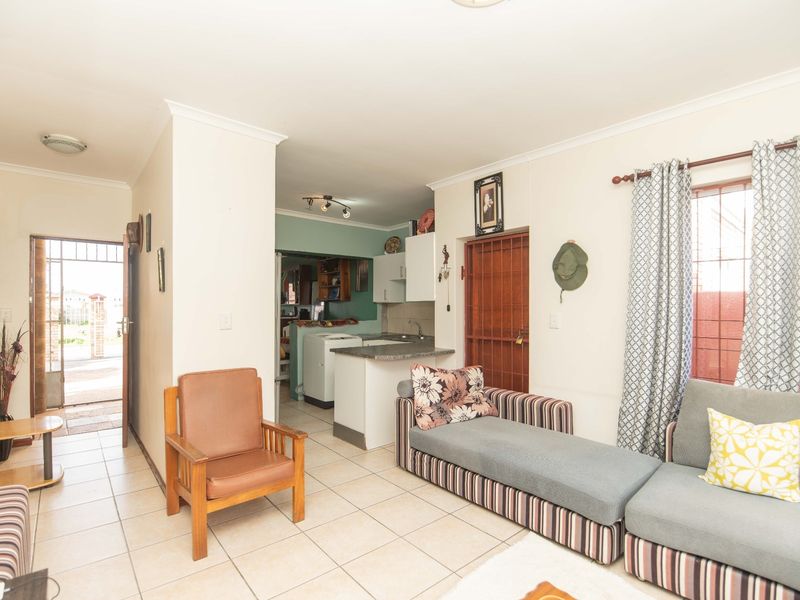 Open plan living area featuring tiled flooring and a compact kitchen with built-in cabinetry and sink, providing a functional layout.