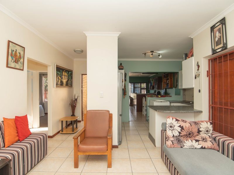 Open-plan living area featuring tiled flooring, a breakfast bar, and a functional kitchen layout with direct access to adjacent rooms.