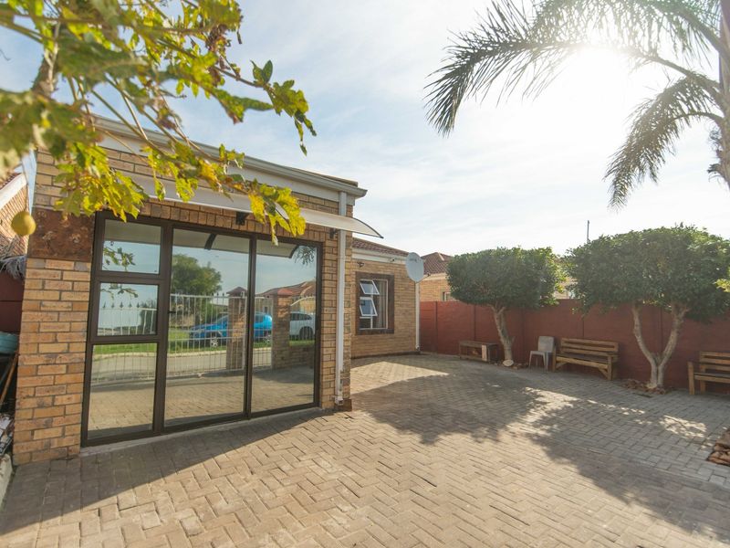 A well-maintained rear courtyard featuring brick paving, face brick exterior walls, and secure aluminium sliding door access.