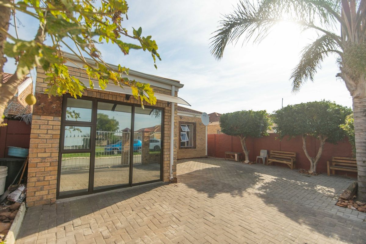 A well-maintained rear courtyard featuring brick paving, face brick exterior walls, and secure aluminium sliding door access.