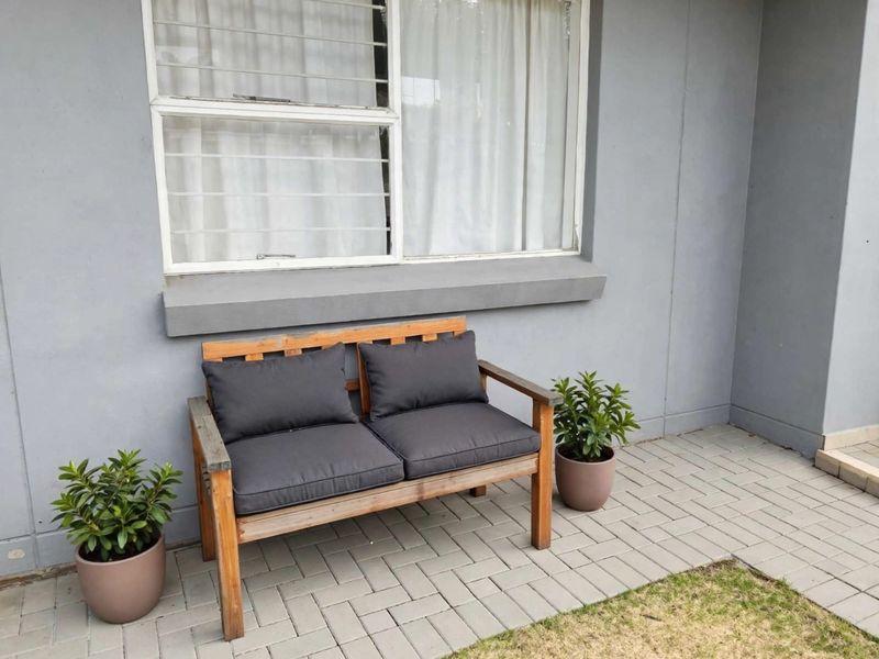 A neat paved patio area featuring a sliding window with security bars, providing a clean and functional outdoor space.