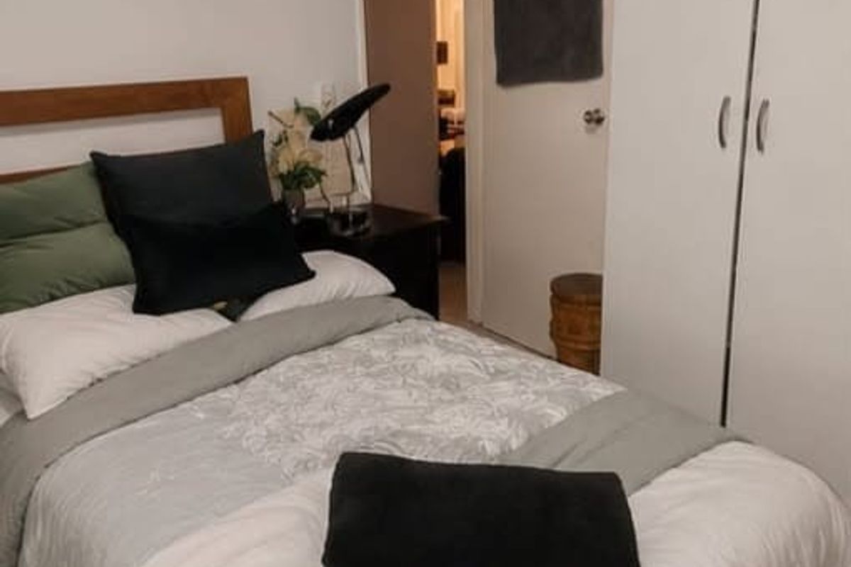 A bedroom featuring a built-in wardrobe and neutral wall finishes, providing a functional sleeping space.