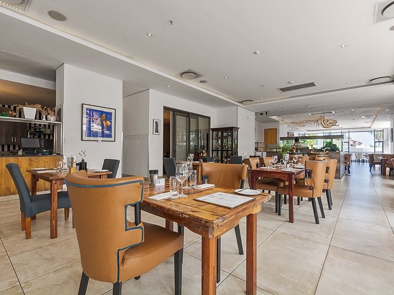 Spacious open-plan dining area featuring tiled flooring, recessed ceiling lighting, and a built-in service counter, suitable for commercial or residential use.