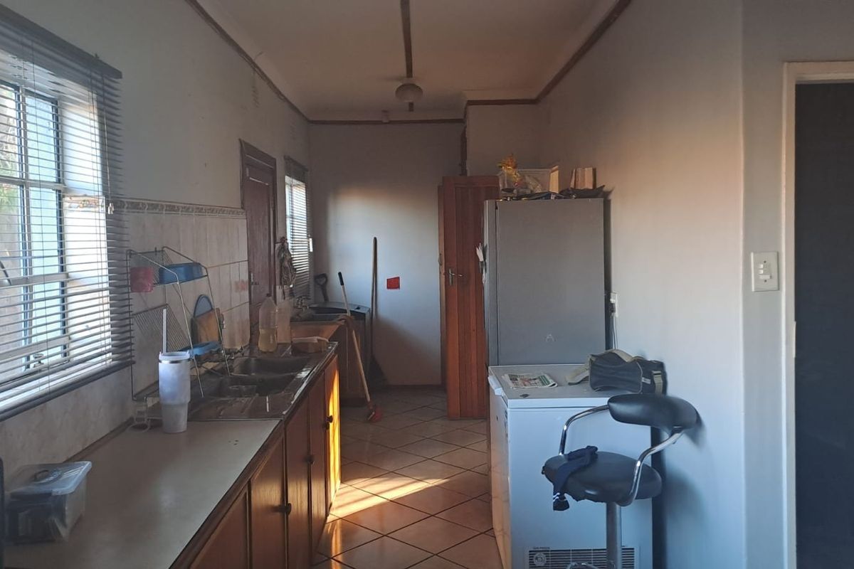 A functional kitchen space featuring tiled flooring, a double sink, and built-in cabinetry with a tiled splashback.
