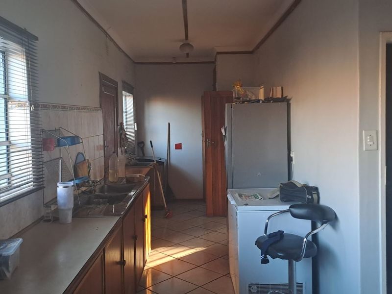 A functional kitchen space featuring tiled flooring, a double sink, and built-in cabinetry with a tiled splashback.