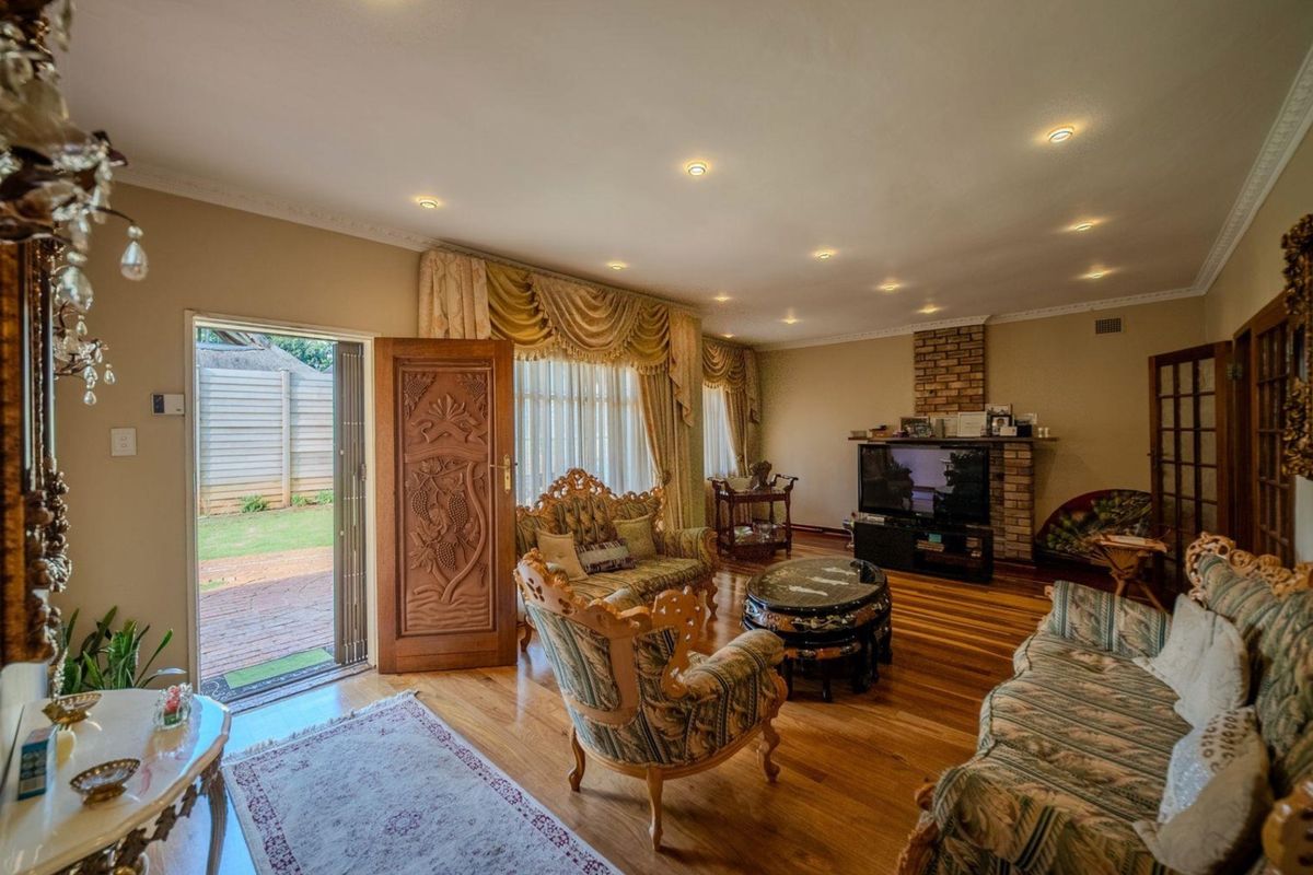 Spacious living room featuring polished hardwood flooring, recessed downlighting, a brick fireplace, and direct access to the outdoor patio area.