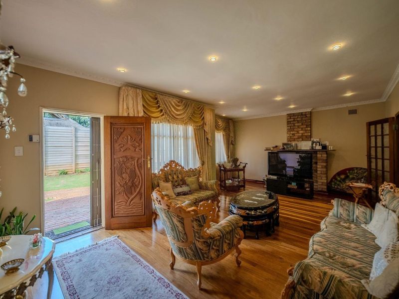 Spacious living room featuring polished hardwood flooring, recessed downlighting, a brick fireplace, and direct access to the outdoor patio area.