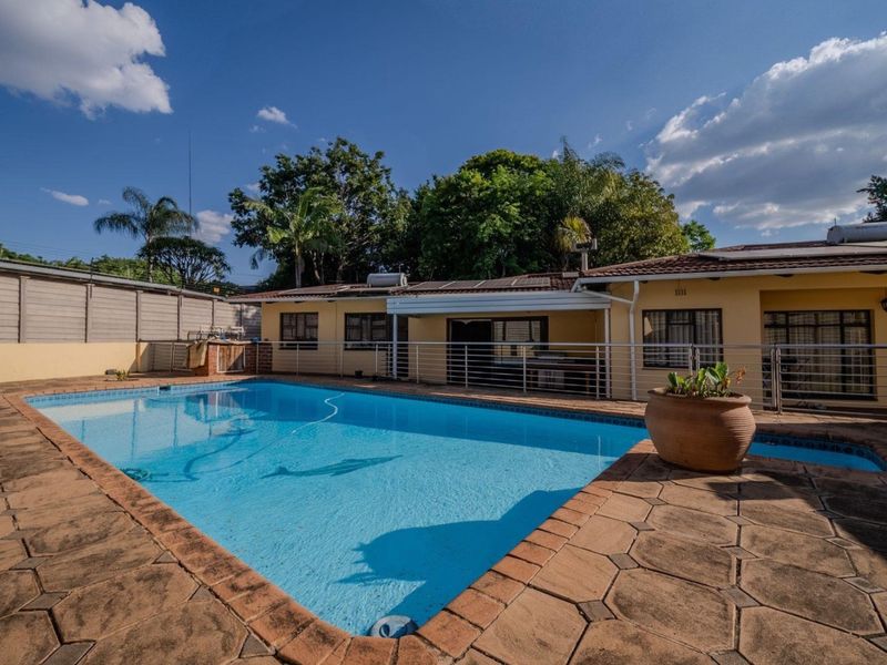 Outdoor pool area featuring a paved deck, metal safety railing, and solar water heating panels on the roof of the main dwelling.