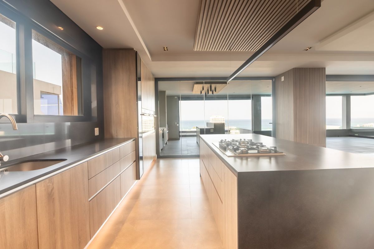 Modern kitchen featuring sleek wood-finish cabinetry, a large central island with a gas cooktop, and premium finishes with an open-plan layout.