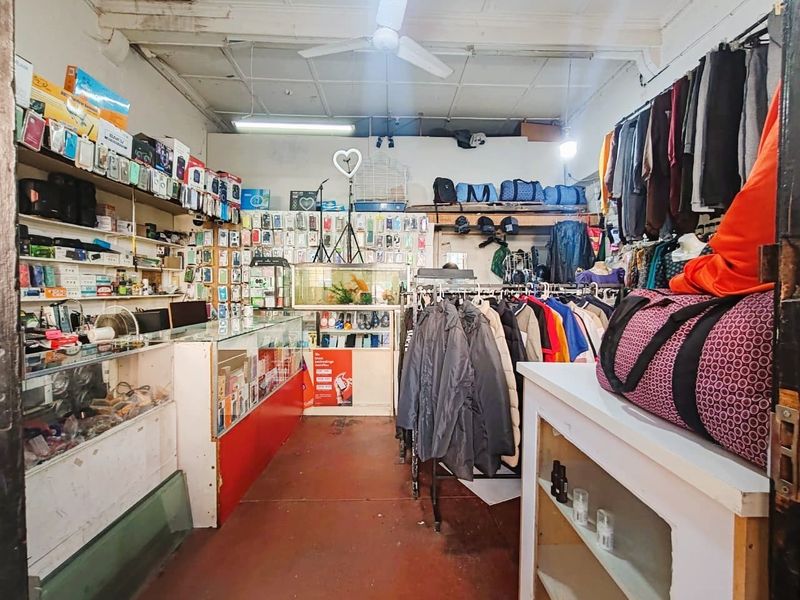 Interior view of a retail space featuring built-in shelving units, overhead lighting, and a ceiling fan, currently utilized for merchandise display.