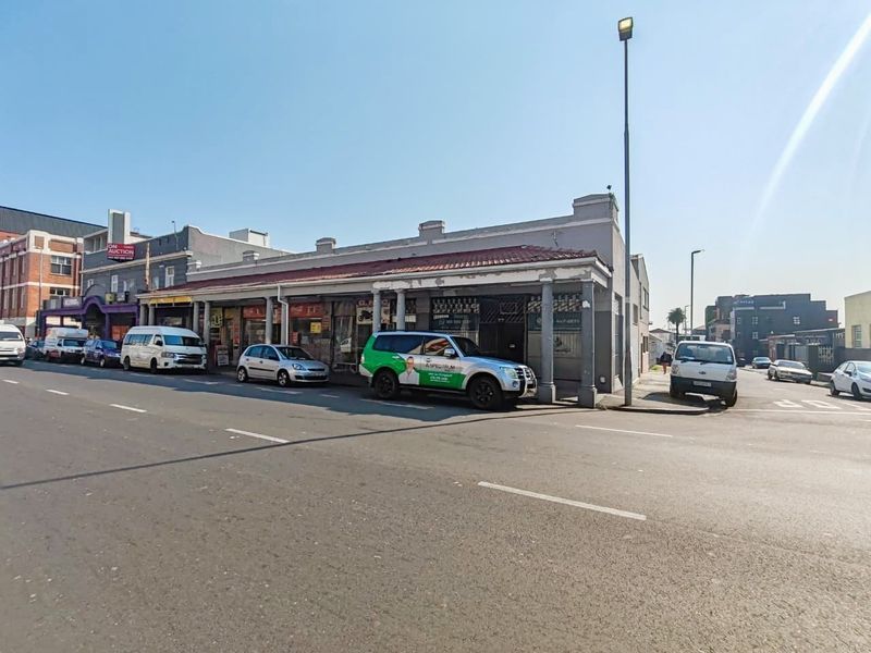 Street-level view of a retail property featuring a covered walkway with support columns and a tiled roof facade.