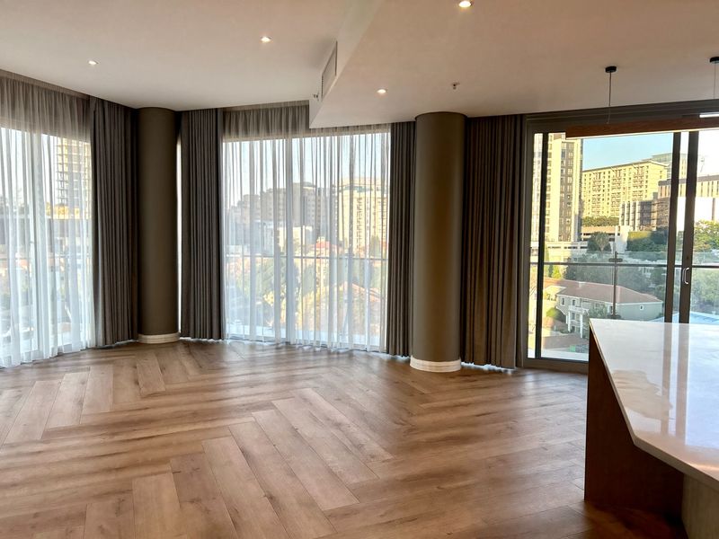 Spacious open-plan living area featuring premium herringbone timber flooring, floor-to-ceiling windows with city views, and modern recessed lighting.
