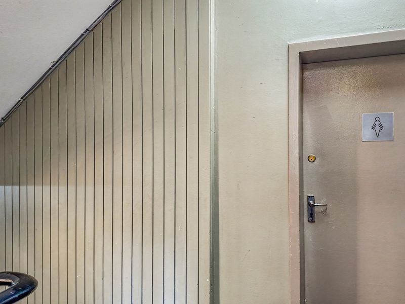 A commercial hallway featuring vertical timber wall paneling and a designated female restroom door with standard hardware.
