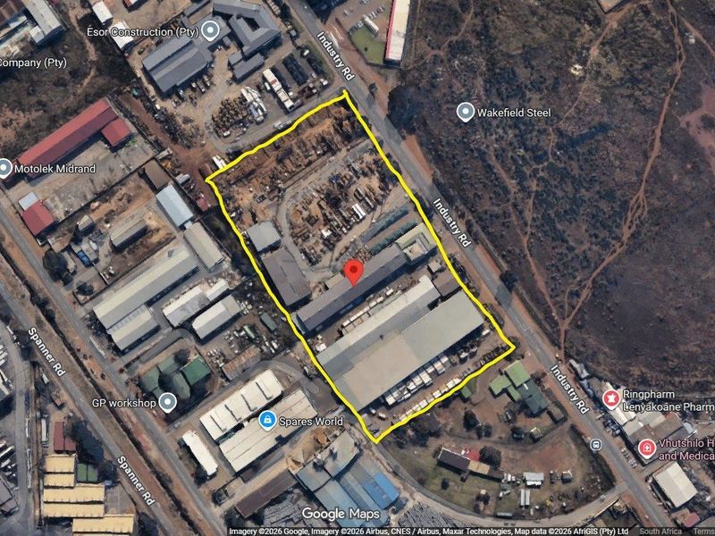 Aerial view of a commercial industrial property featuring multiple warehouse structures, a large yard area, and direct access from Industry Road.