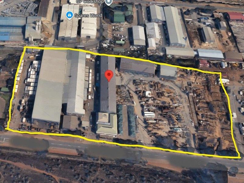 Aerial view of a commercial industrial property featuring multiple warehouse structures and a large yard area with road access.