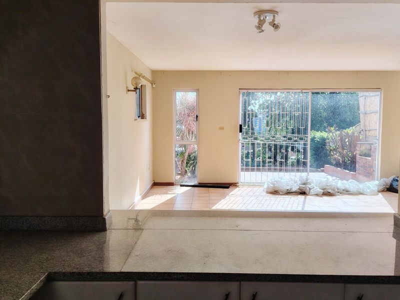 An open-plan living area featuring tiled flooring, a granite breakfast bar, and large sliding glass doors leading to an outdoor space.