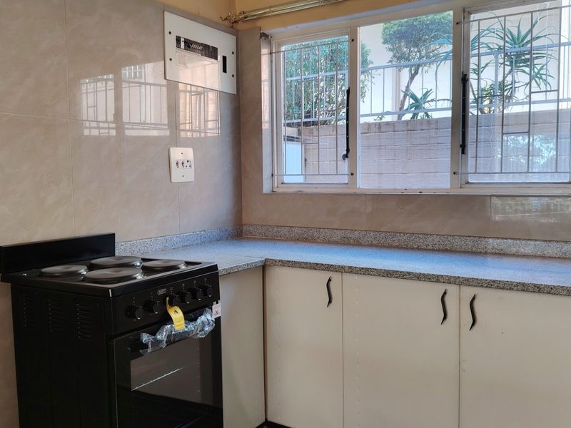 A clean, functional kitchen featuring granite countertops, white cabinetry, and a modern electric stove, complemented by natural light from the window.